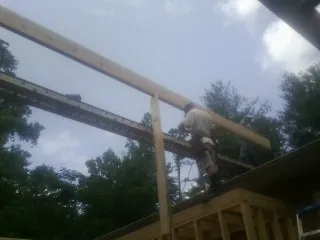 Carpenter setting a ridge beam over a new addition frame in Melvindale