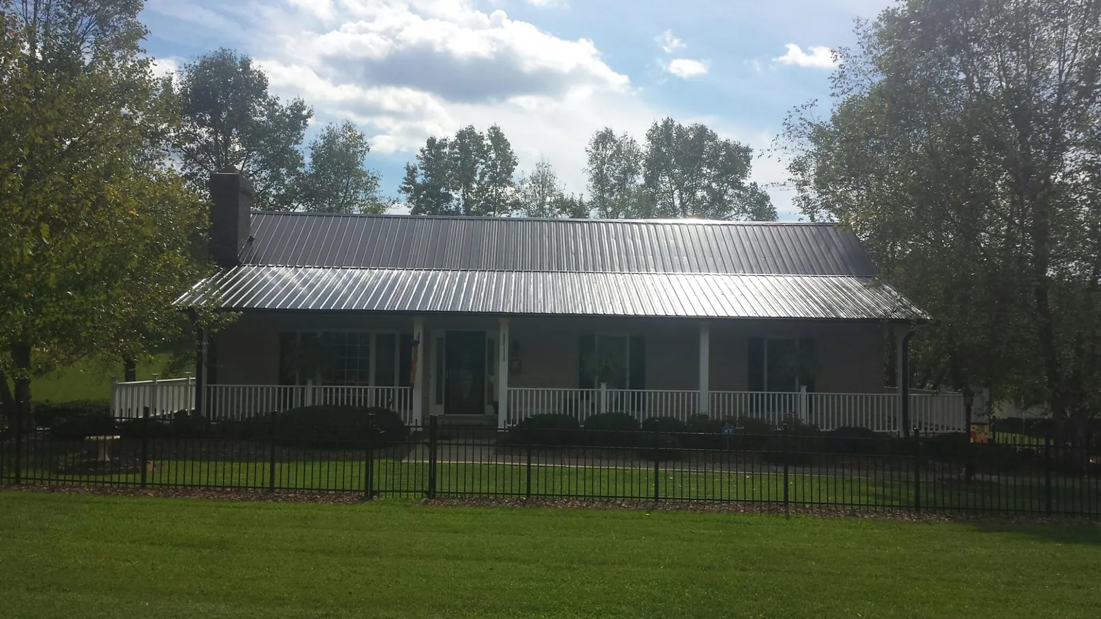 Gray metal roof on a brick ranch with a full width front porch — Gutter Guard Installation work by our crew in Melvindale