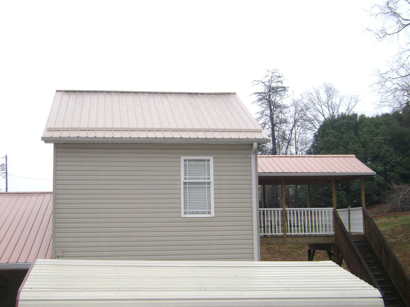 Tan metal roofs on a two story addition and attached porch, from a Roof Replacement job in Melvindale