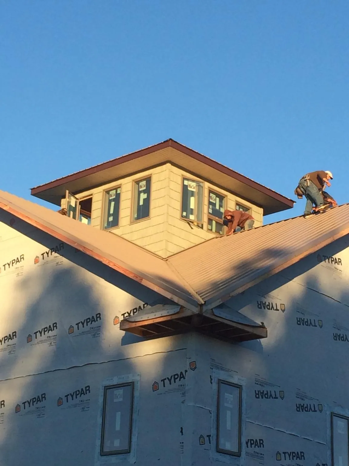 Roofers working around a rooftop cupola on a new metal roof at sunset — Roof Waterproofing in Melvindale by Roofing Brothers